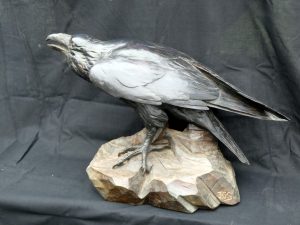 woodcarving of a raven, in carved cedar wood and paint wax finish